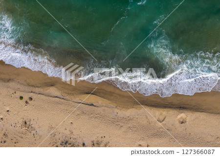 Aerial view of a remote sandy beach and sea waves 127366087
