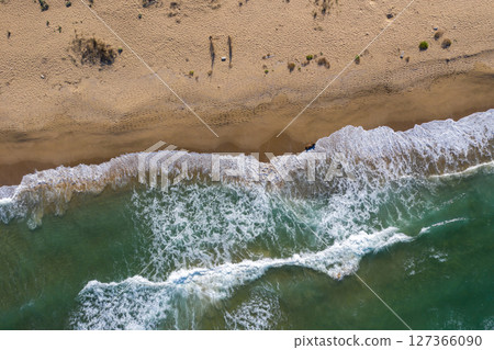 Aerial view of sea waves and a remote secluded sandy beach 127366090