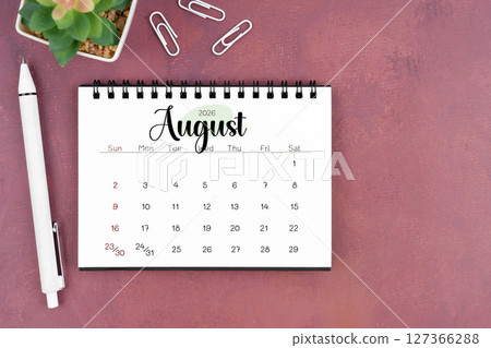 August desk calendar for 2026 year and pen on old red cover. Flat lay. August desk calendar for 2026 year and pen on old red cover. Flat lay. 127366288