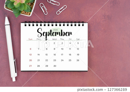 September desk calendar for 2026 year and pen on old red cover. Flat lay. September desk calendar for 2026 year and pen on old red cover. Flat lay. 127366289