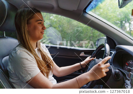 A young girl is driving a car. an inexperienced driver.  127367018