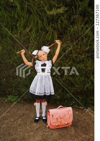 Cheerful schoolgirl in school uniform with funny ponytails and white bows. Cheerful schoolgirl in school uniform with funny ponytails and white bows. 127367100