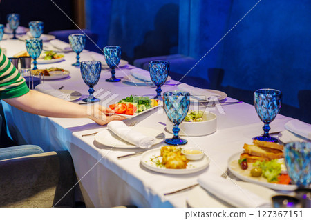 A festive table with cutlery and snacks in a dark room of the restaurant. A festive table with cutlery and snacks in a dark room of the restaurant. 127367151