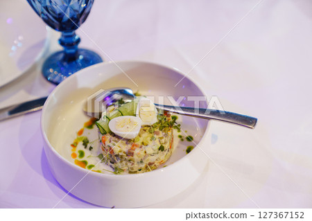 Classic Olivier salad, Moscow salad in a serving plate with a spoon Classic Olivier salad, Moscow salad in a serving plate with a spoon 127367152