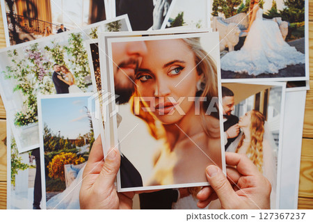 Men's hands put on the table and show wedding photos. 127367237