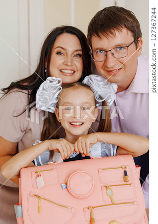 Cute happy schoolgirl with mom and dad. Beautiful school uniform.  127367244
