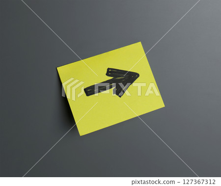 A bright yellow sticky note displays a black arrow indicating right A bright yellow sticky note displays a black arrow indicating right 127367312