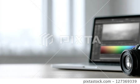 Laptop screen shows color grading, next to camera, World Photography Day concept 127369339