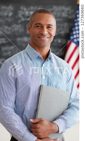 Teacher holds a book and stands proudly in front of students with the USA flag on Labor Day 127369660