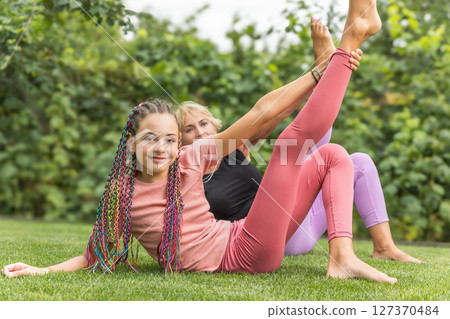 Girl and mature woman are doing gymnastics outside 127370484