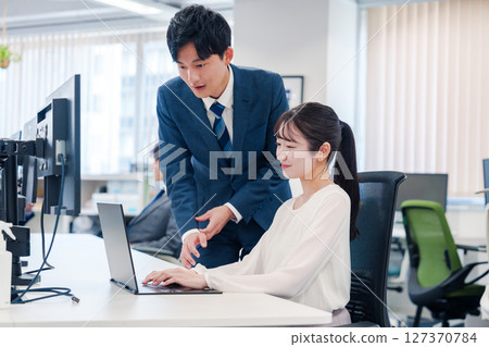 A young female office worker being taught how to do her job by her senior 127370784