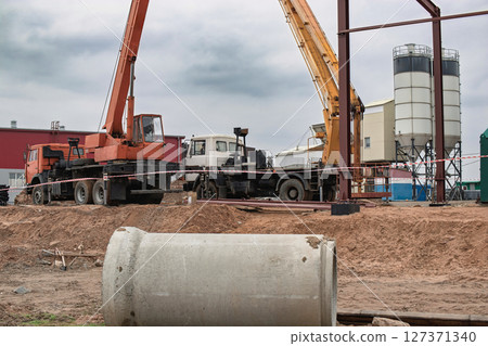 Construction site with heavy machinery operating in cloudy weather near a building Construction site with heavy machinery operating in cloudy weather near a building 127371340