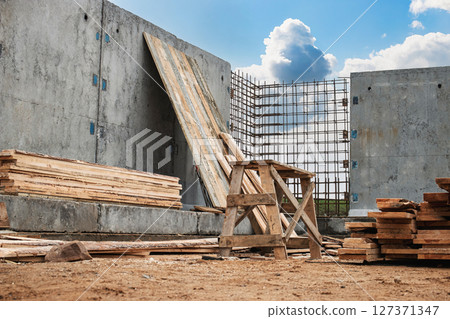 Construction site with wooden materials and steel reinforcement under clear blue sky Construction site with wooden materials and steel reinforcement under clear blue sky 127371347