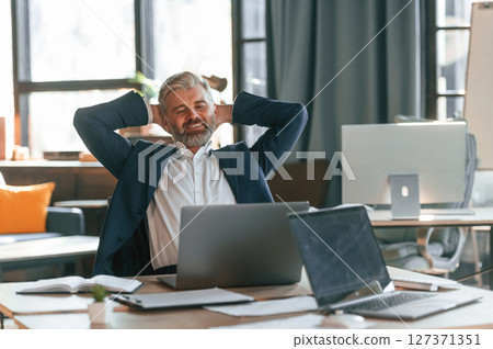 Taking a break, satisfied with success. Senior businessman is working in the office 127371351