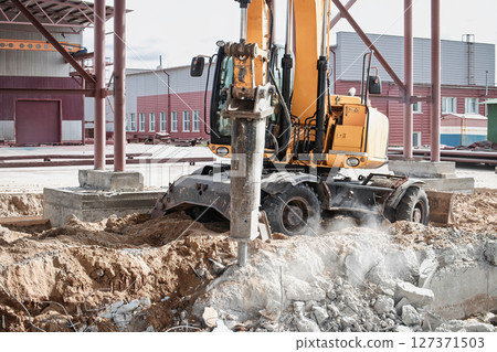 Construction equipment breaking ground at a building site in urban area during daylight hours 127371503