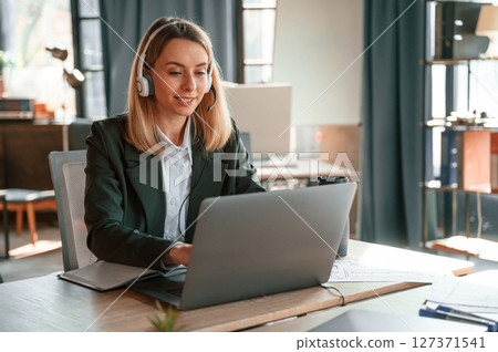 Using laptop. Young beautiful woman in formal clothes is working in the office Using laptop. Young beautiful woman in formal clothes is working in the office 127371541