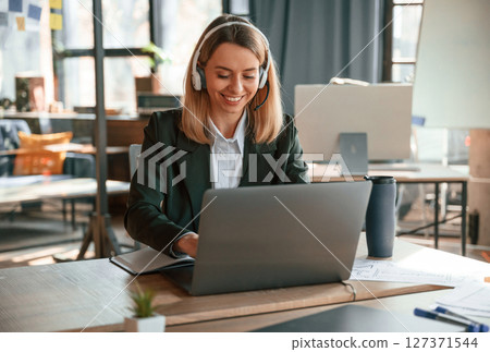 Smiling, using laptop. Young beautiful woman in formal clothes is working in the office Smiling, using laptop. Young beautiful woman in formal clothes is working in the office 127371544