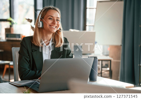 Smiling, using laptop. Young beautiful woman in formal clothes is working in the office Smiling, using laptop. Young beautiful woman in formal clothes is working in the office 127371545