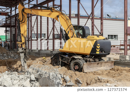 Professional demolition of reinforced concrete structures using industrial hydraulic hammer with excavator. Rods of metal fittings. Wreckage and crumbles of concrete. Professional demolition of reinforced concrete structures using industrial hydraulic hammer with excavator. Rods of metal fittings. Wreckage and crumbles of concrete. 127371574