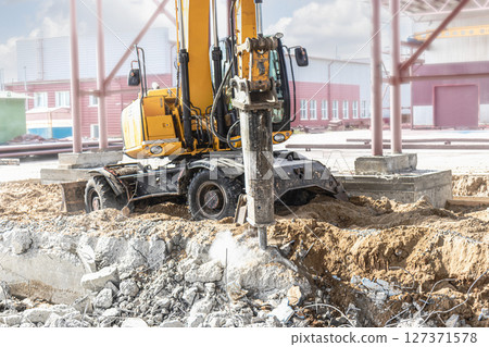 Professional demolition of reinforced concrete structures using industrial hydraulic hammer with excavator. Rods of metal fittings. Wreckage and crumbles of concrete. Professional demolition of reinforced concrete structures using industrial hydraulic hammer with excavator. Rods of metal fittings. Wreckage and crumbles of concrete. 127371578