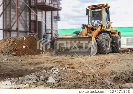 A powerful front loader on the construction site performs sanding. Moving soil with construction equipment. Excavation. 127371598