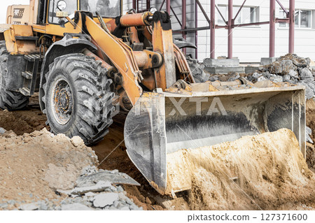 A powerful front loader on the construction site performs sanding. Moving soil with construction equipment. Excavation. 127371600