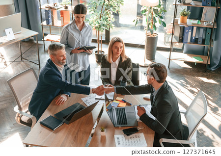 Successful deal, doing handshake. Group of business people are working in the modern office 127371645