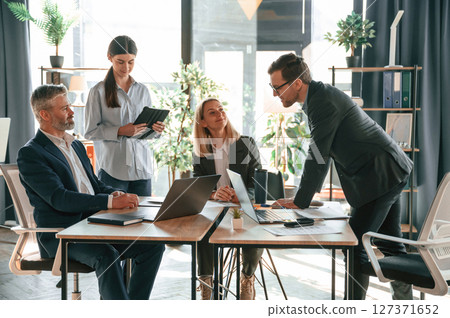 Busy workers are by the table. Group of business people are in the modern office Busy workers are by the table. Group of business people are in the modern office 127371652