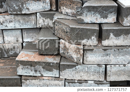 Stacked grey bricks with a textured surface displayed in construction setting during daylight hours Stacked grey bricks with a textured surface displayed in construction setting during daylight hours 127371757