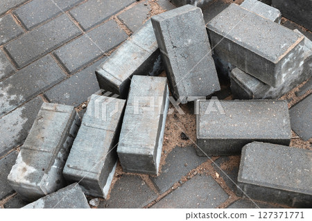 Construction materials scattered on a pavement during building work in an urban area Construction materials scattered on a pavement during building work in an urban area 127371771