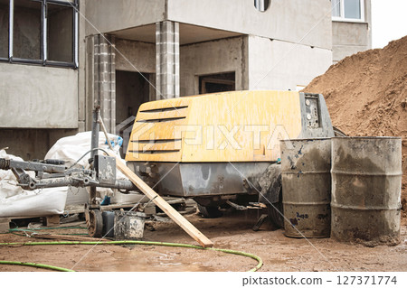 Construction site equipment rests near a building under development during overcast afternoon light 127371774