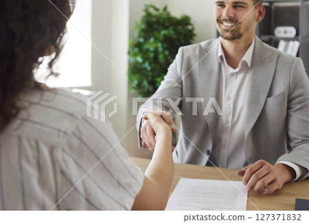 Business people sitting in office on workplace making a deal. Man shaking hand with woman. 127371832