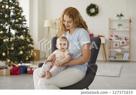 Happy young mother and her adorable little baby spending Christmas holidays at home 127371833