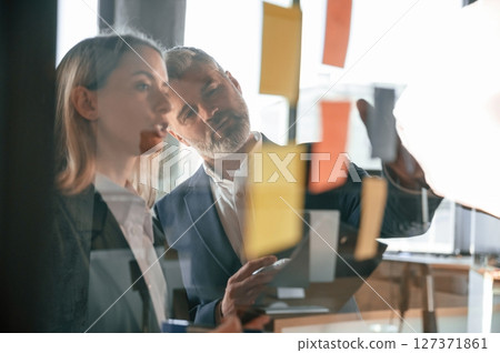 Creating the plan. Putting stickers on the glass. Business people are working together in the office 127371861