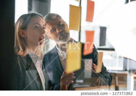 Creating the plan. Putting stickers on the glass. Business people are working together in the office Creating the plan. Putting stickers on the glass. Business people are working together in the office 127371862