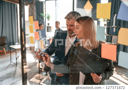 Conception of plan. Many stickers are on the glass. Group of business people are working in the modern office 127371872