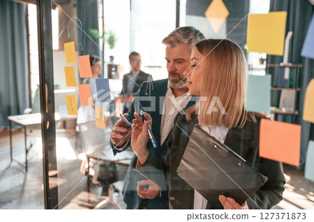 Conception of plan. Many stickers are on the glass. Group of business people are working in the modern office Conception of plan. Many stickers are on the glass. Group of business people are working in the modern office 127371873