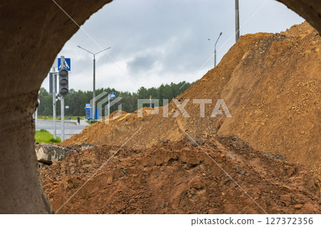 Soil excavation at the construction site. A pile of sand and earth after earthworks. Trench in the ground. 127372356