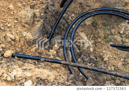 The high voltage electrical cable is laid in a trench under existing engineering sewerage networks. Laying a high voltage cable for supplying buildings with electricity. The high voltage electrical cable is laid in a trench under existing engineering sewerage networks. Laying a high voltage cable for supplying buildings with electricity. 127372363