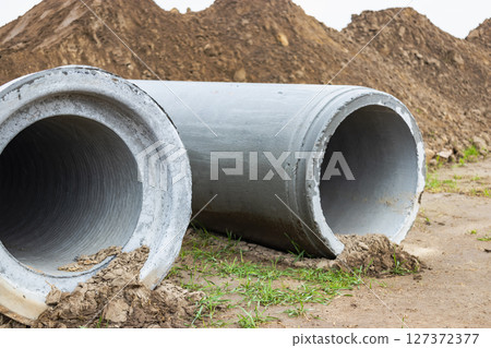 Reinforced concrete storm sewer pipes of large diameter stacked at a construction site. Sewer Large diameter pipes. Wastewater disposal in a modern city. Reinforced concrete storm sewer pipes of large diameter stacked at a construction site. Sewer Large diameter pipes. Wastewater disposal in a modern city. 127372377