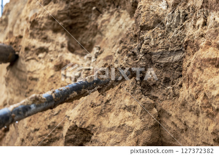 The high voltage electrical cable is laid in a trench under existing engineering sewerage networks. Laying a high voltage cable for supplying buildings with electricity. The high voltage electrical cable is laid in a trench under existing engineering sewerage networks. Laying a high voltage cable for supplying buildings with electricity. 127372382