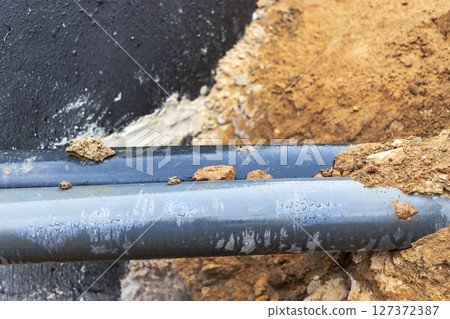 The high voltage electrical cable is laid in a trench under existing engineering sewerage networks. Laying a high voltage cable for supplying buildings with electricity. The high voltage electrical cable is laid in a trench under existing engineering sewerage networks. Laying a high voltage cable for supplying buildings with electricity. 127372387