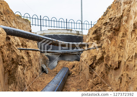 The high voltage electrical cable is laid in a trench under existing engineering sewerage networks. Laying a high voltage cable for supplying buildings with electricity. 127372392
