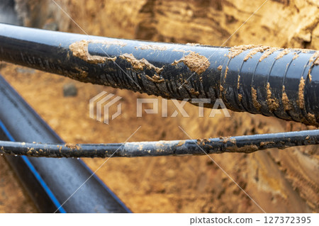 The high voltage electrical cable is laid in a trench under existing engineering sewerage networks. Laying a high voltage cable for supplying buildings with electricity. 127372395