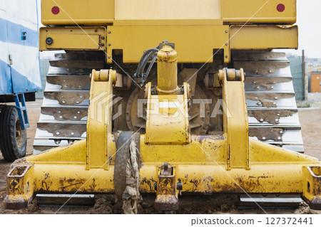 Bulldozer machine is leveling construction site. Earthmover with tractor is moving earth. Close-up. Construction heavy machinery. 127372441