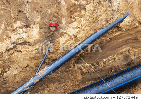 The high voltage electrical cable is laid in a trench under existing engineering sewerage networks. Laying a high voltage cable for supplying buildings with electricity. 127372449