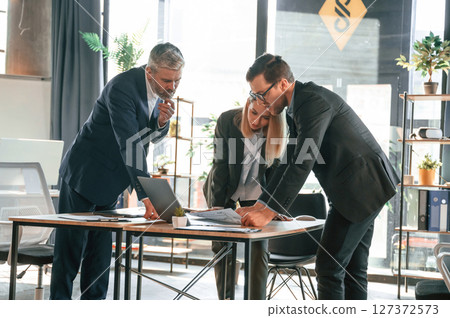 Standing by the table. Group of business people are working in the modern office Standing by the table. Group of business people are working in the modern office 127372573