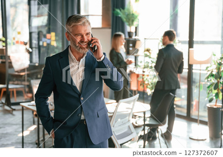 Man is standing and having phone call. Group of business people are working in the modern office 127372607