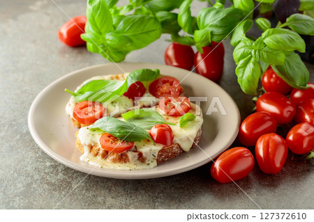 Hot open sandwiches with mozzarella, tomatoes and basil. 127372610