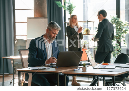 Three people are busy in the office. Group of employees are working together 127372624